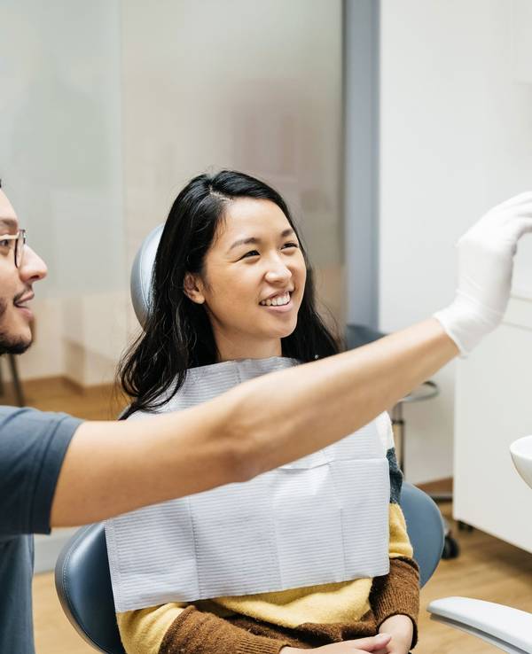 A young patient looking at a monitor and talking to her dentist about her dental health during a check up at his clinic.