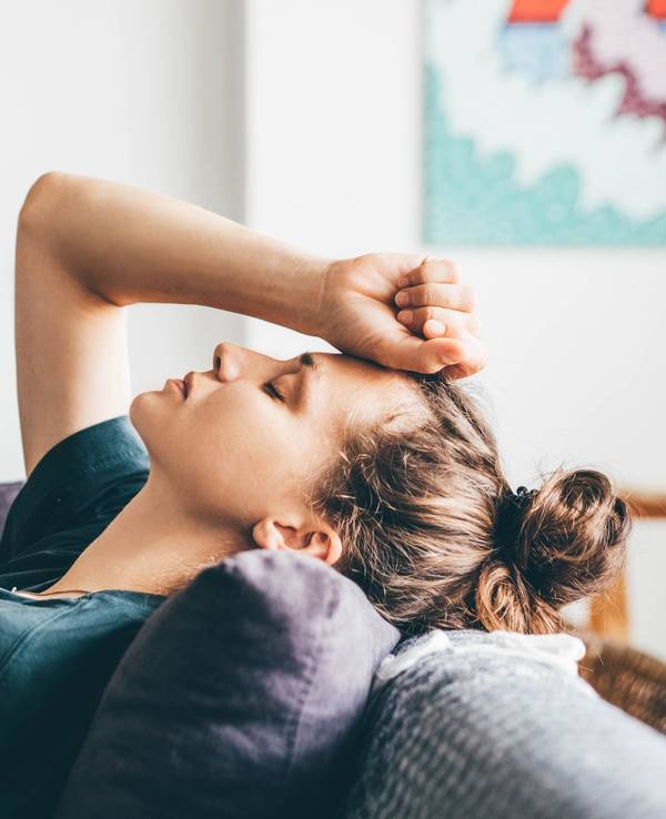 Sad and depressed woman sitting on sofa at home.