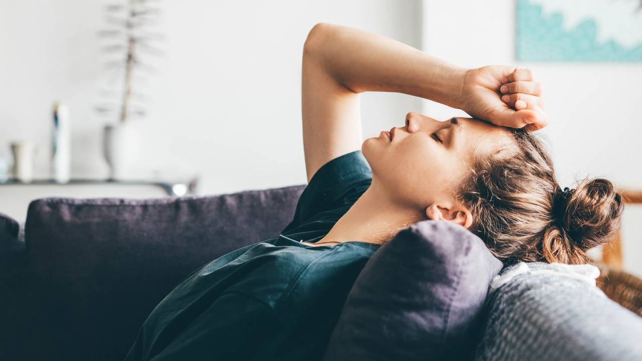 Sad and depressed woman sitting on sofa at home.
