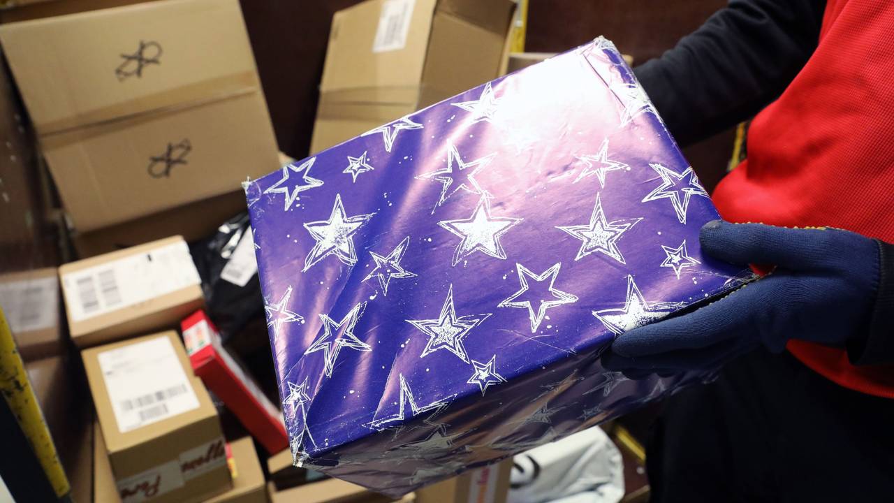 In der DHL-Zustellbasis in Groß Schwaß zeigt ein Mitarbeiter ein weihnachtlich verpacktes Paket.