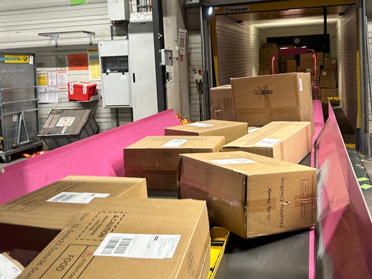 Pakete auf einem Fließband in einem DHL-Paketzentrum.