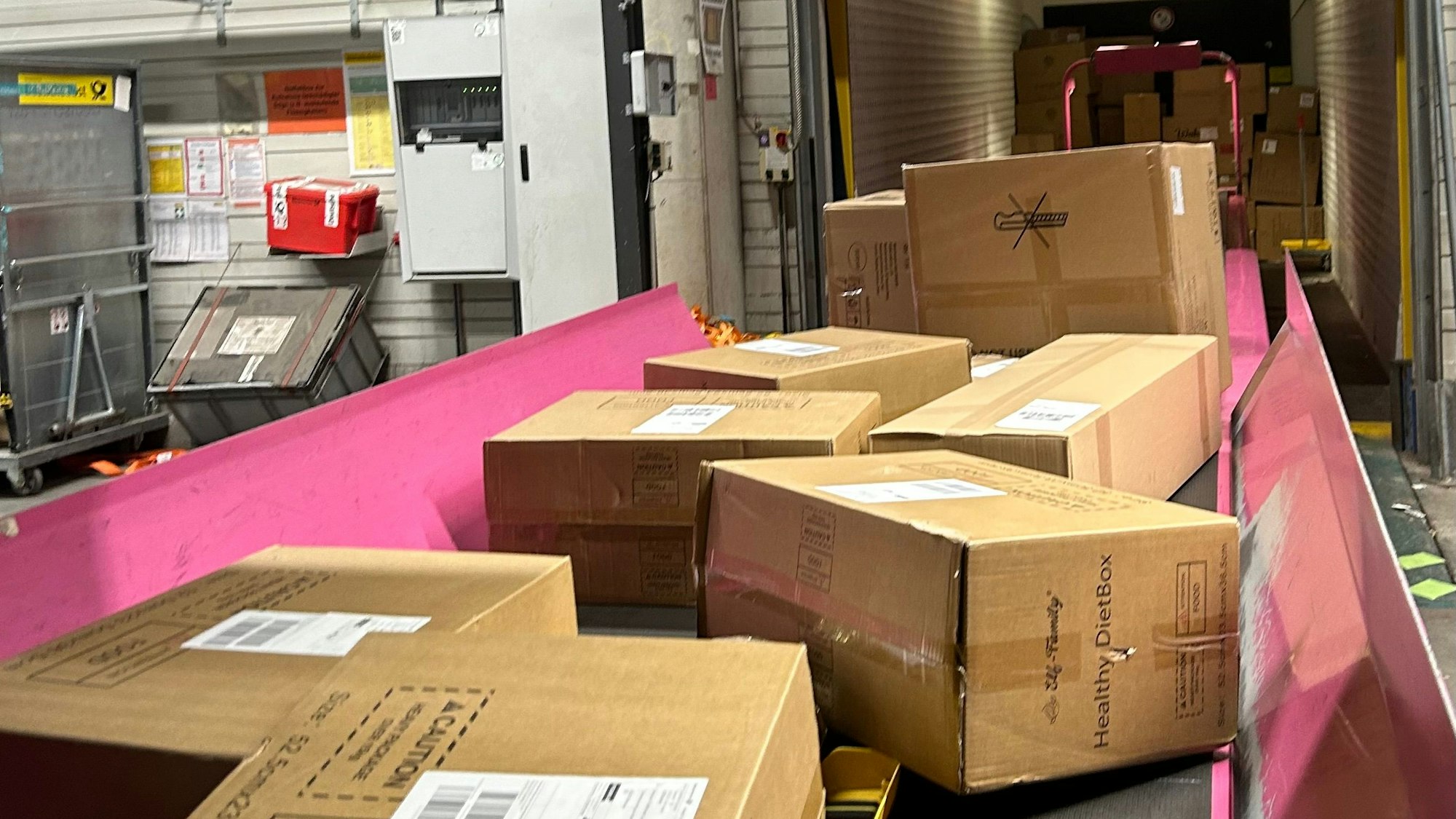 Pakete auf einem Fließband in einem DHL-Paketzentrum.