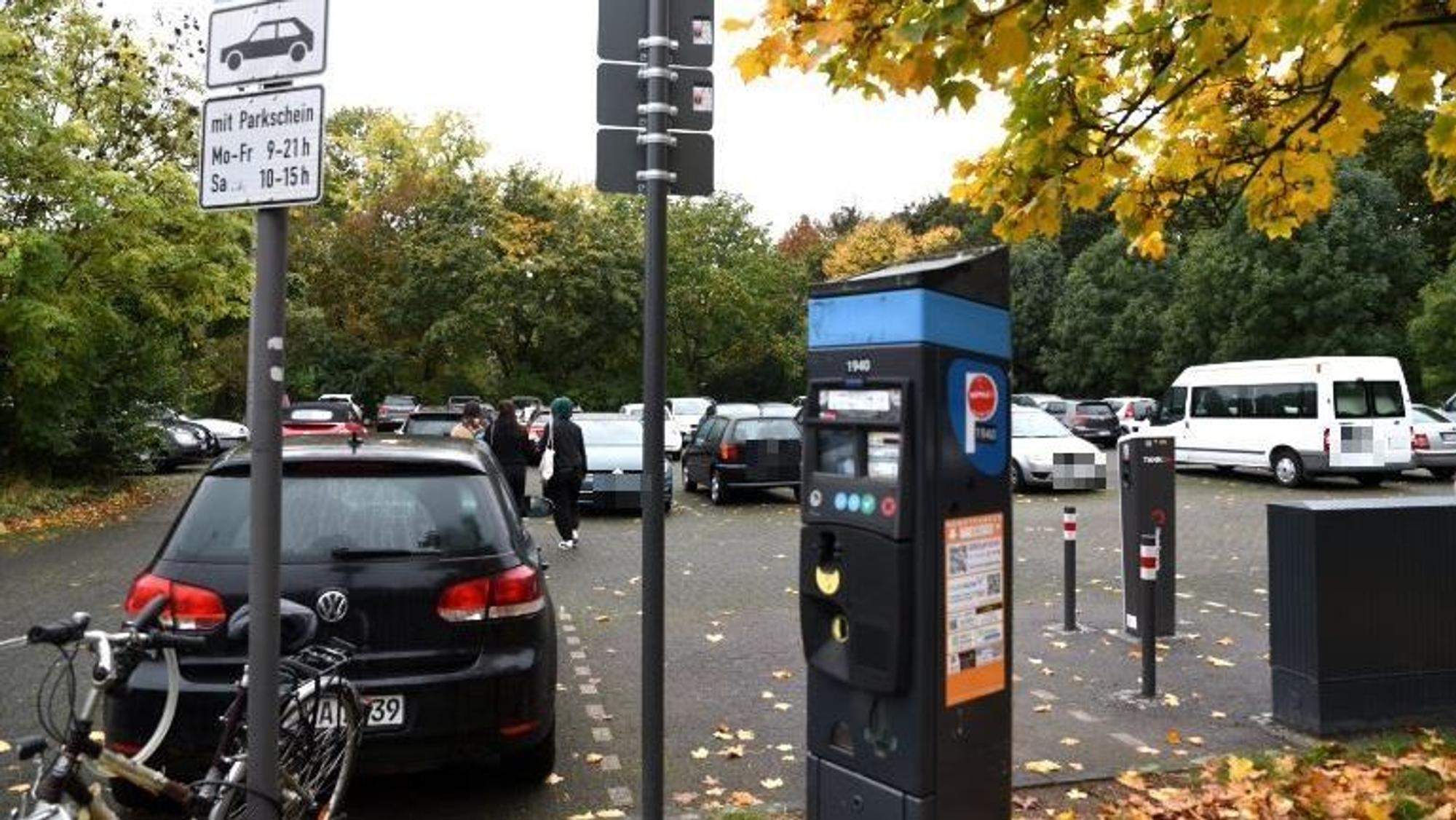 Einige Autos stehen auf einem Parkplatz im Grünen. Auch ein Ticketautomat ist zu sehen.