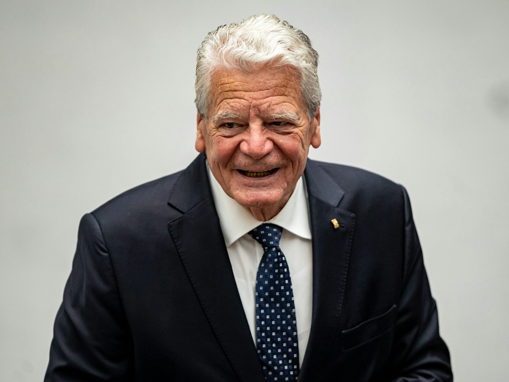 Joachim Gauck geht mit einem Lächeln im Gesicht durch den deutschen Bundestag.