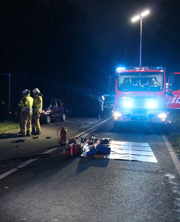 Eine Unfallstelle mit demolierten Autos in der Dunkelheit. Auch ein Feuerwehrauto und Rettungskräfte sind zu sehen.