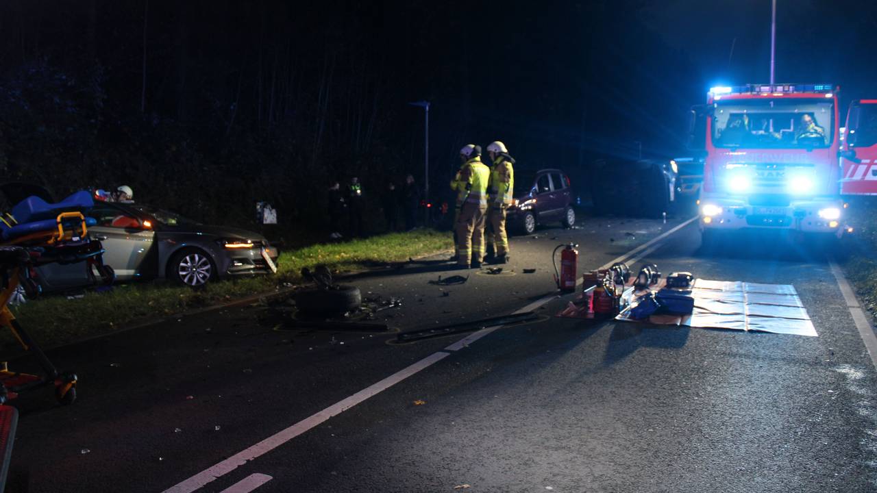 Eine Unfallstelle mit demolierten Autos in der Dunkelheit. Auch ein Feuerwehrauto und Rettungskräfte sind zu sehen.