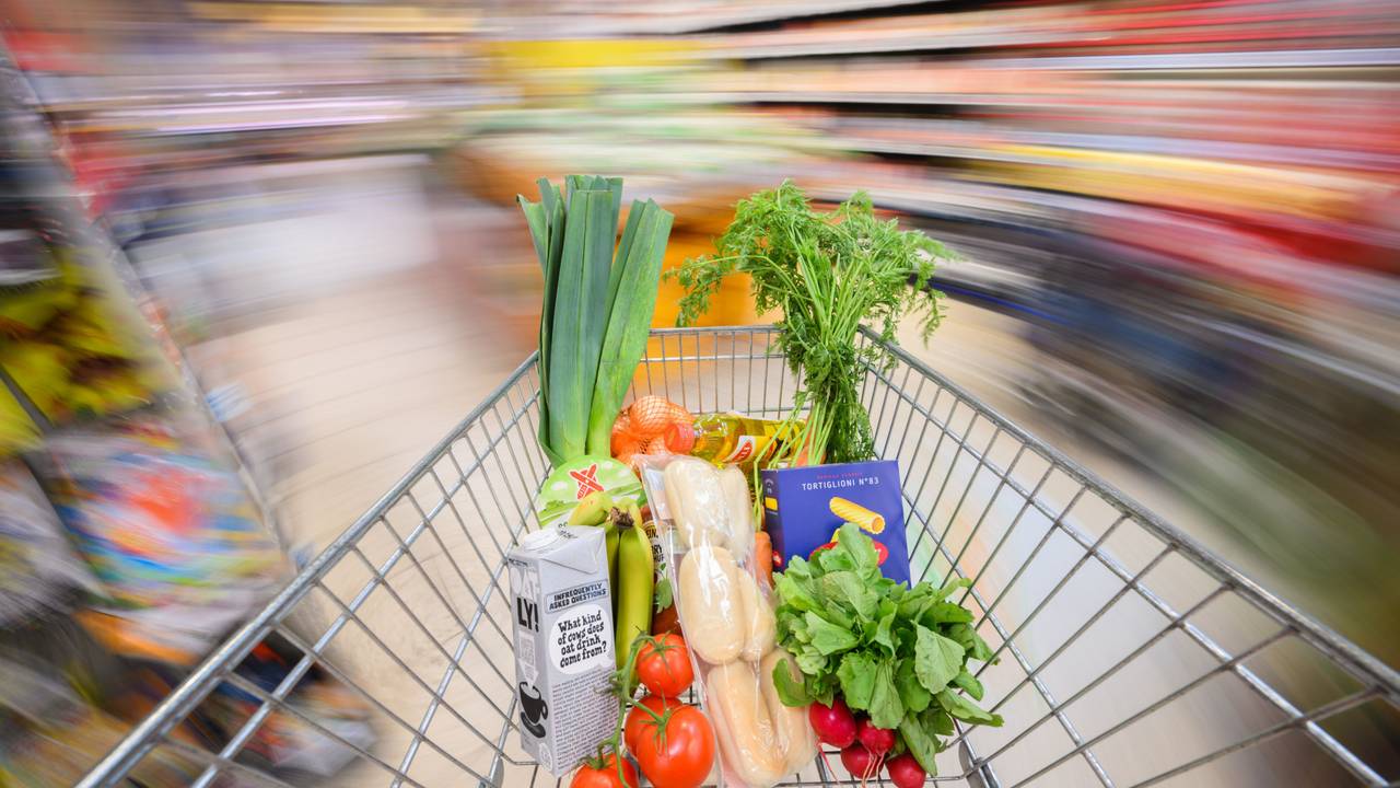 Ein mit Lebensmittel gefüllter Einkaufswagen wird durch einen Supermarkt geschoben.