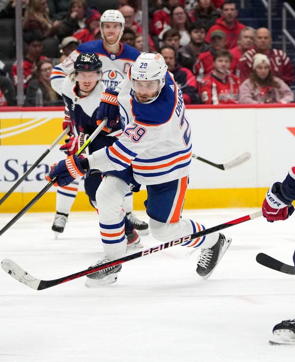 Leon Draisaitl (M) von den Edmonton Oilers schießt am 24. November 2023 ein Tor zwischen Trevor van Riemsdyk (l) von den Washington Capitals und Tom Wilson (r) von den Washington Capitals.