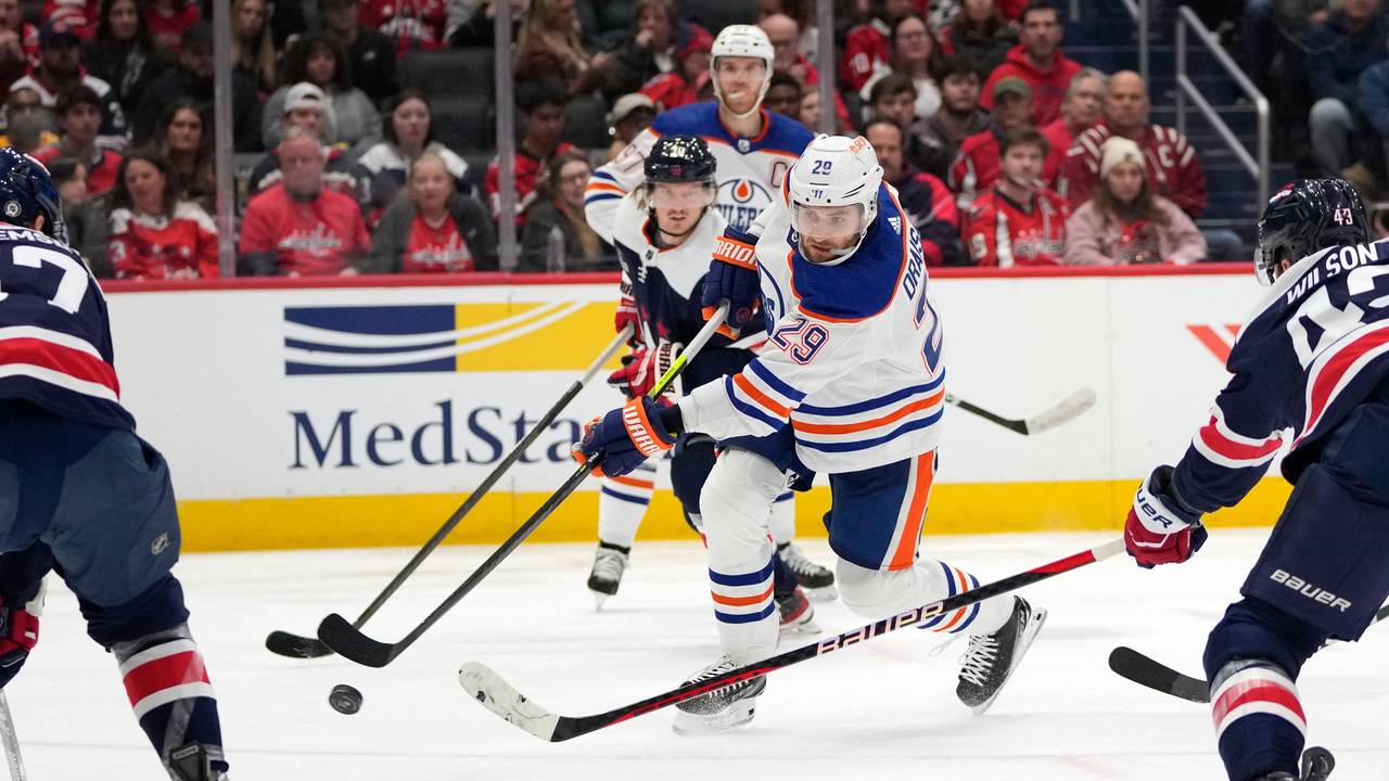 Leon Draisaitl (M) von den Edmonton Oilers schießt am 24. November 2023 ein Tor zwischen Trevor van Riemsdyk (l) von den Washington Capitals und Tom Wilson (r) von den Washington Capitals.