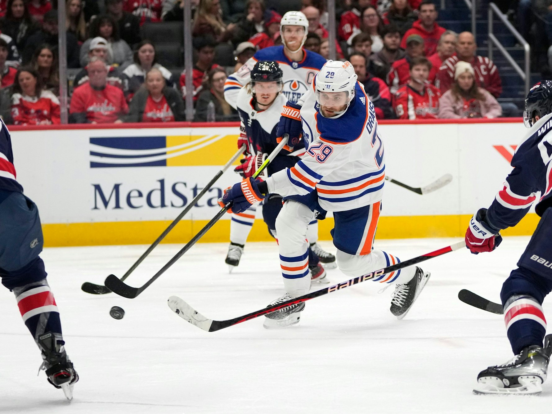 Leon Draisaitl (M) von den Edmonton Oilers schießt am 24. November 2023 ein Tor zwischen Trevor van Riemsdyk (l) von den Washington Capitals und Tom Wilson (r) von den Washington Capitals.