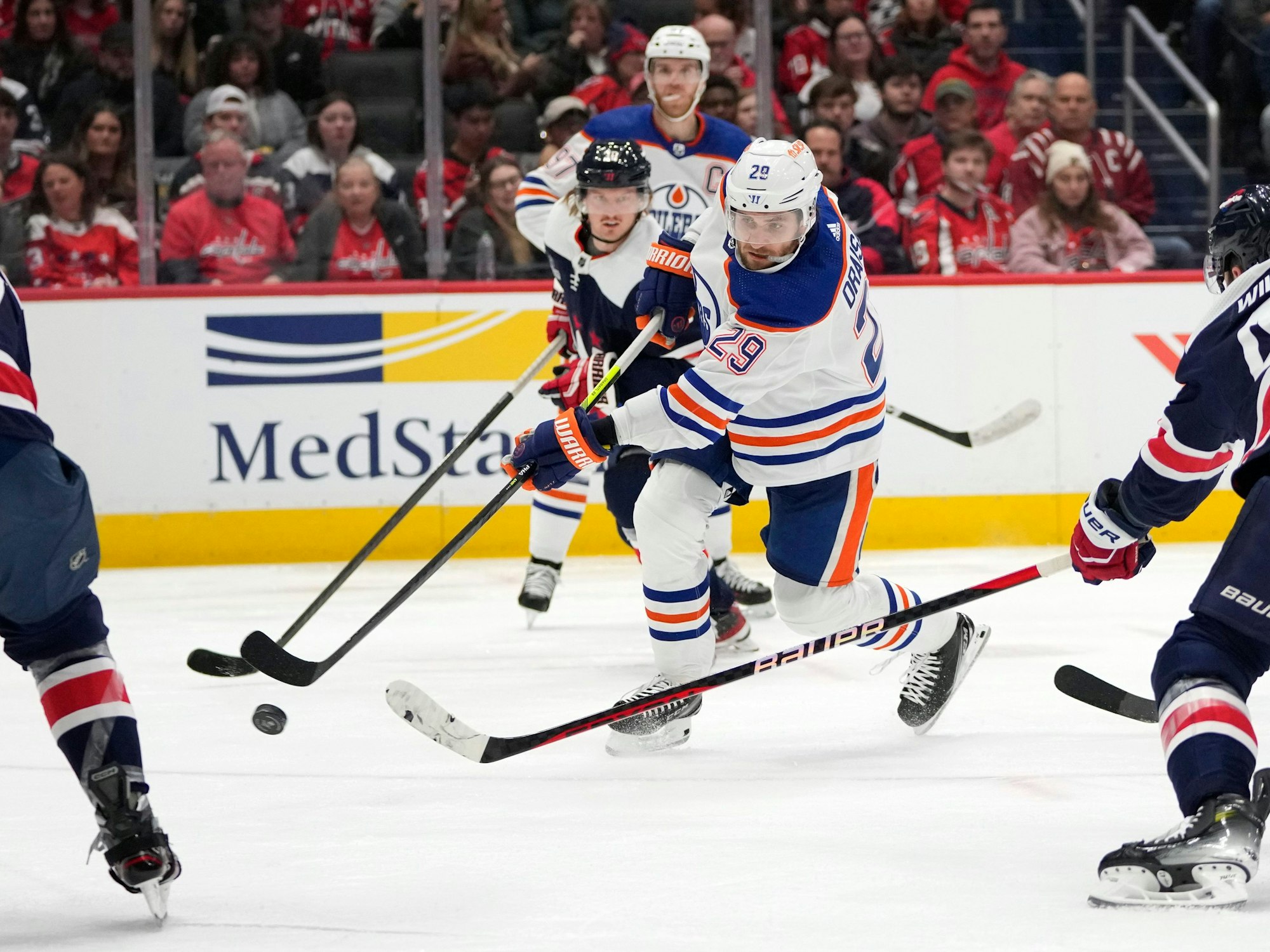 Leon Draisaitl (M) von den Edmonton Oilers schießt am 24. November 2023 ein Tor zwischen Trevor van Riemsdyk (l) von den Washington Capitals und Tom Wilson (r) von den Washington Capitals.