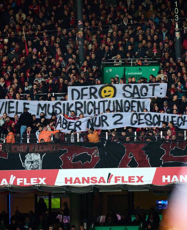 Fans von Bayer Leverkusen halten ein queerfeindliches Plakat hoch
