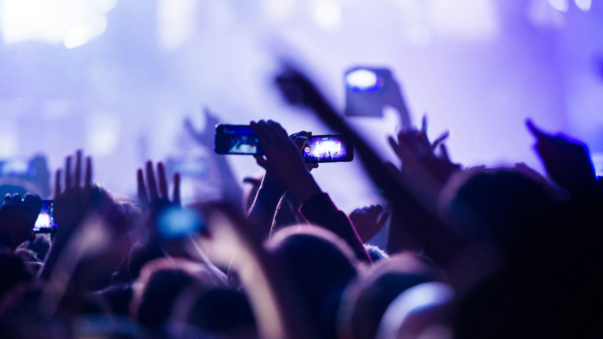 Konzertbesucherinnen und -besucher filmen während eines Konzerts.