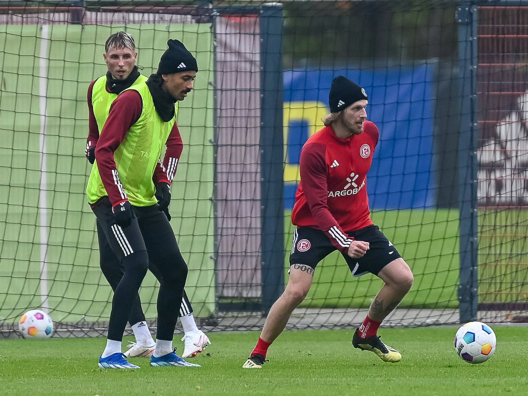 Betreuer Nils Kriszio führt den Ball auf dem Trainingsplatz. Daneben stehen Jona Niemiec und Emmanuel Iyoha.