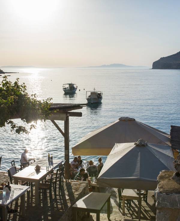 Menschen sitzen in einem Restaurant am Meer.