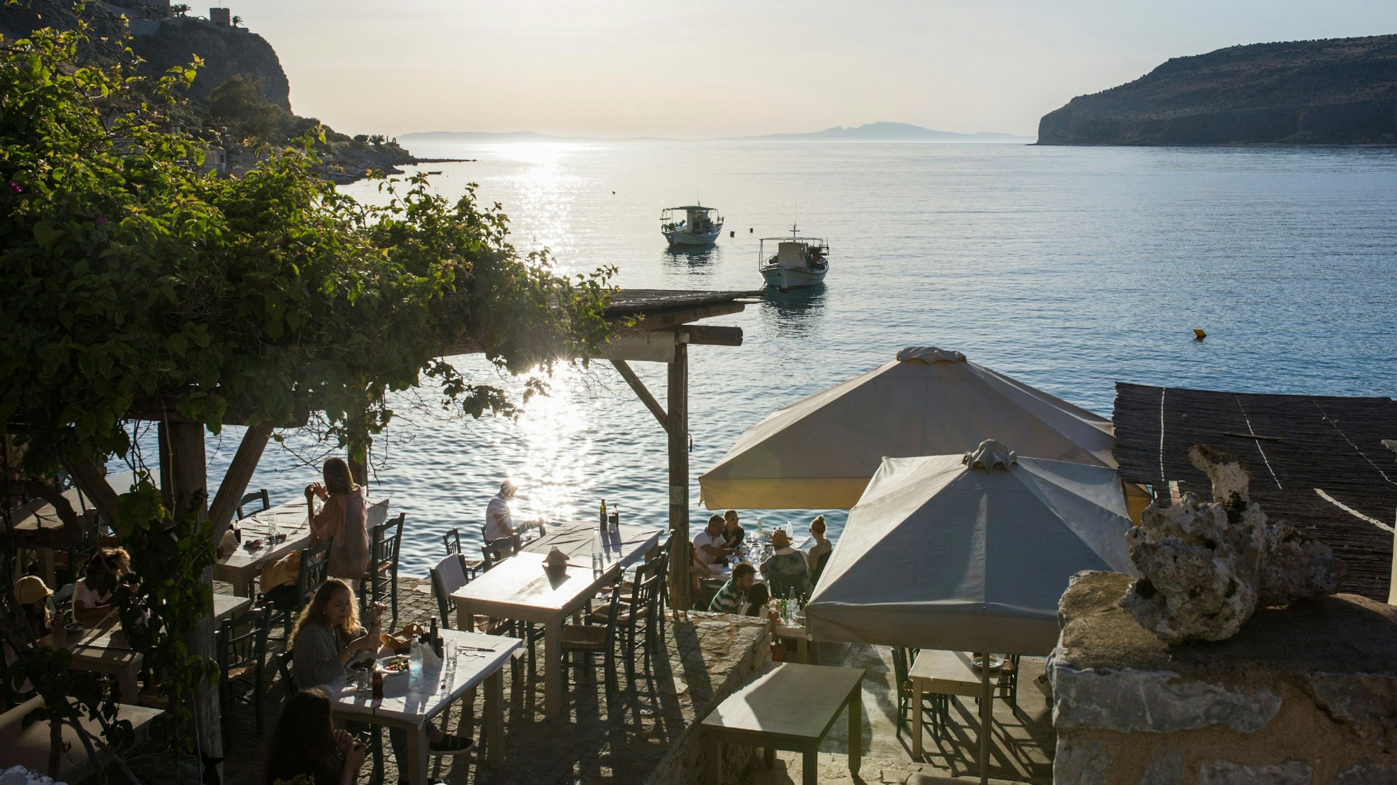 Menschen sitzen in einem Restaurant am Meer.