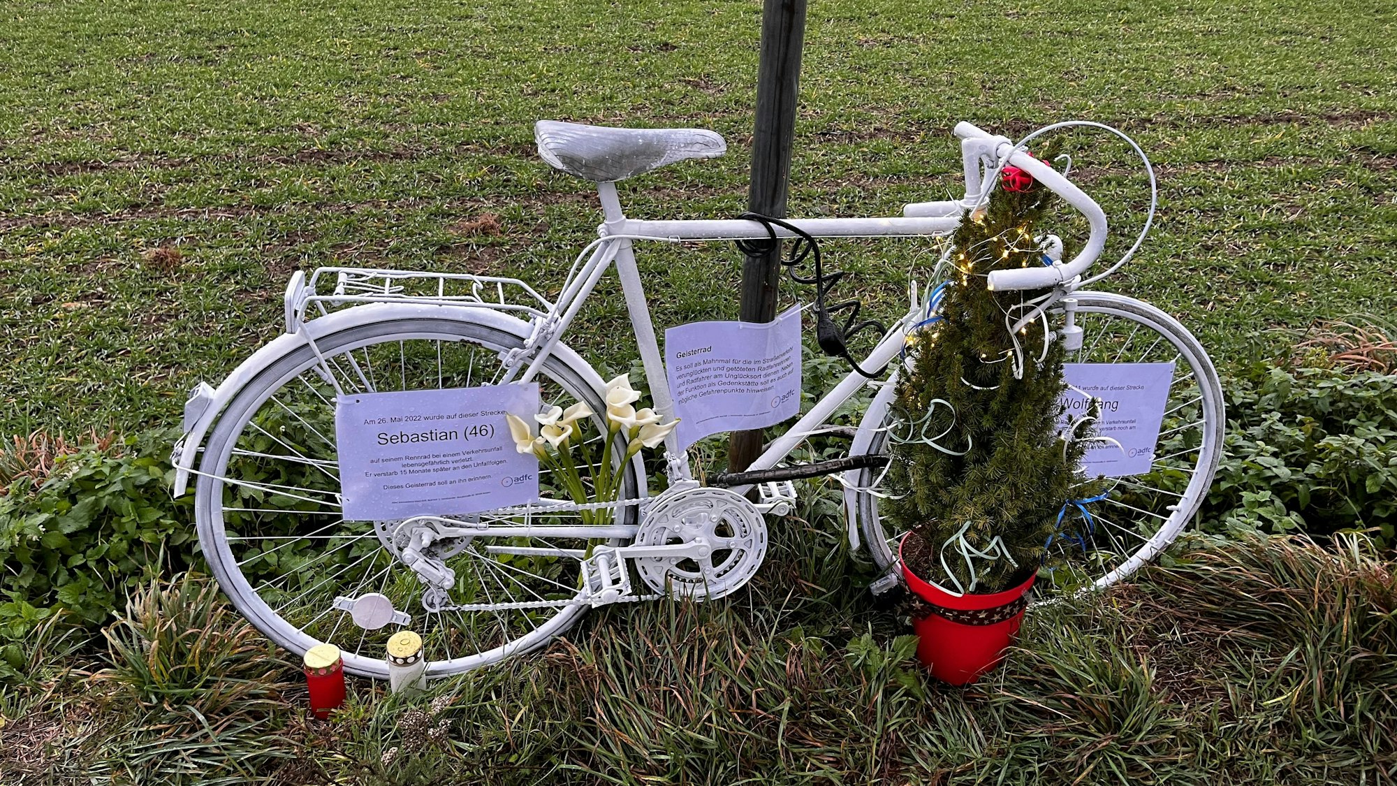 Ein weißes Fahrrad steht an der Straße.