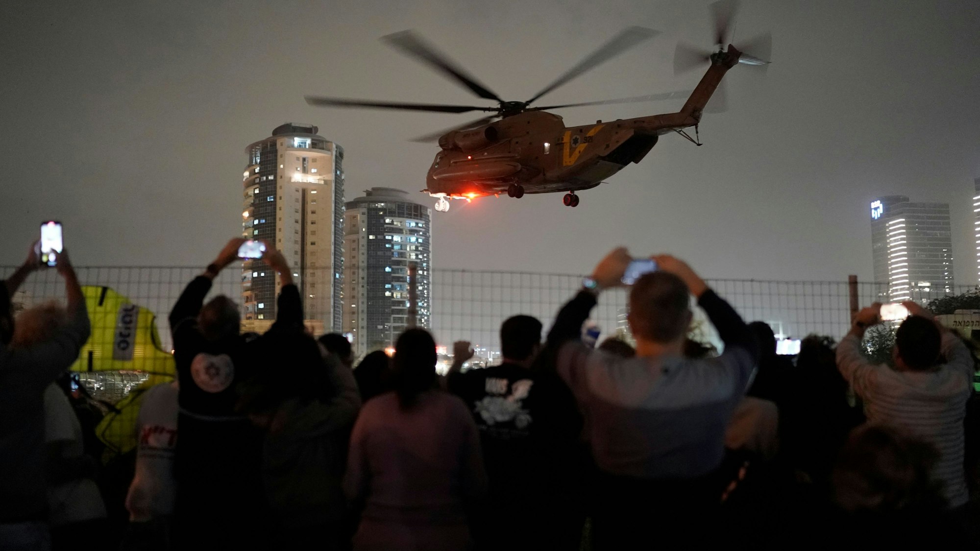 Menschen filmen einen anfliegenden Hubschrauber mit Geiseln, die von der ismalistischen Hamas aus dem Gazastreifen frei gelassen wurden, am Hubschrauberlandeplatz des Schneider Children's Medical Center.