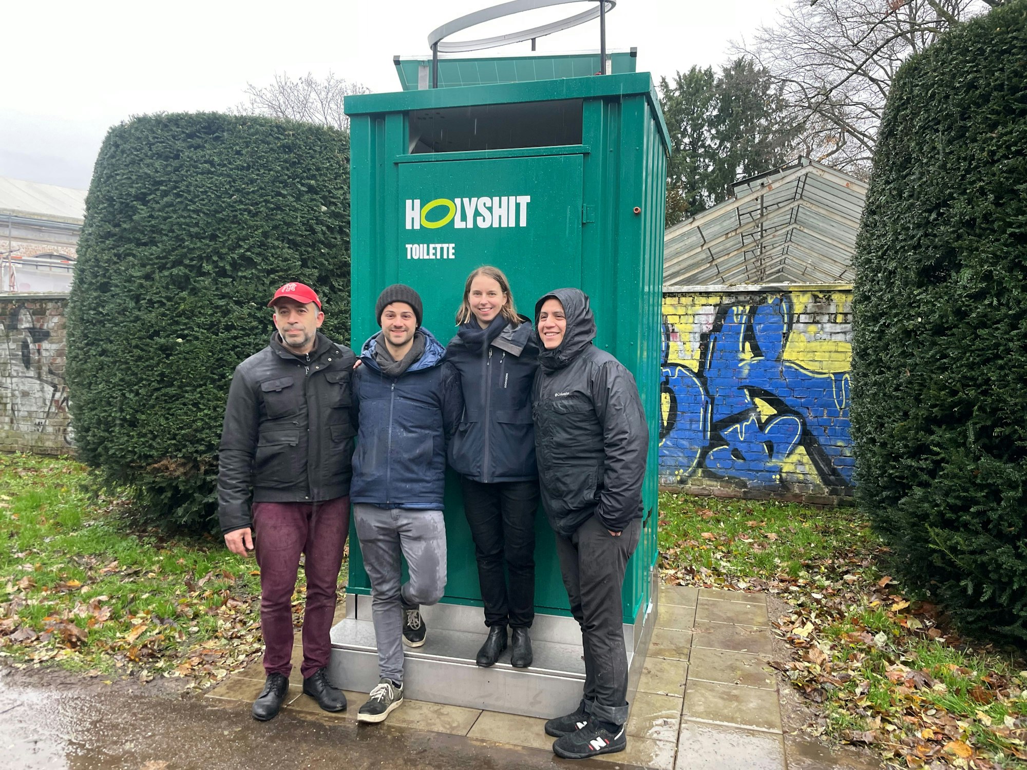 Anastasia Bondar steht gemeinsam mit ihrem Team vor der ersten „Holy Shit“-Toilette in Köln.