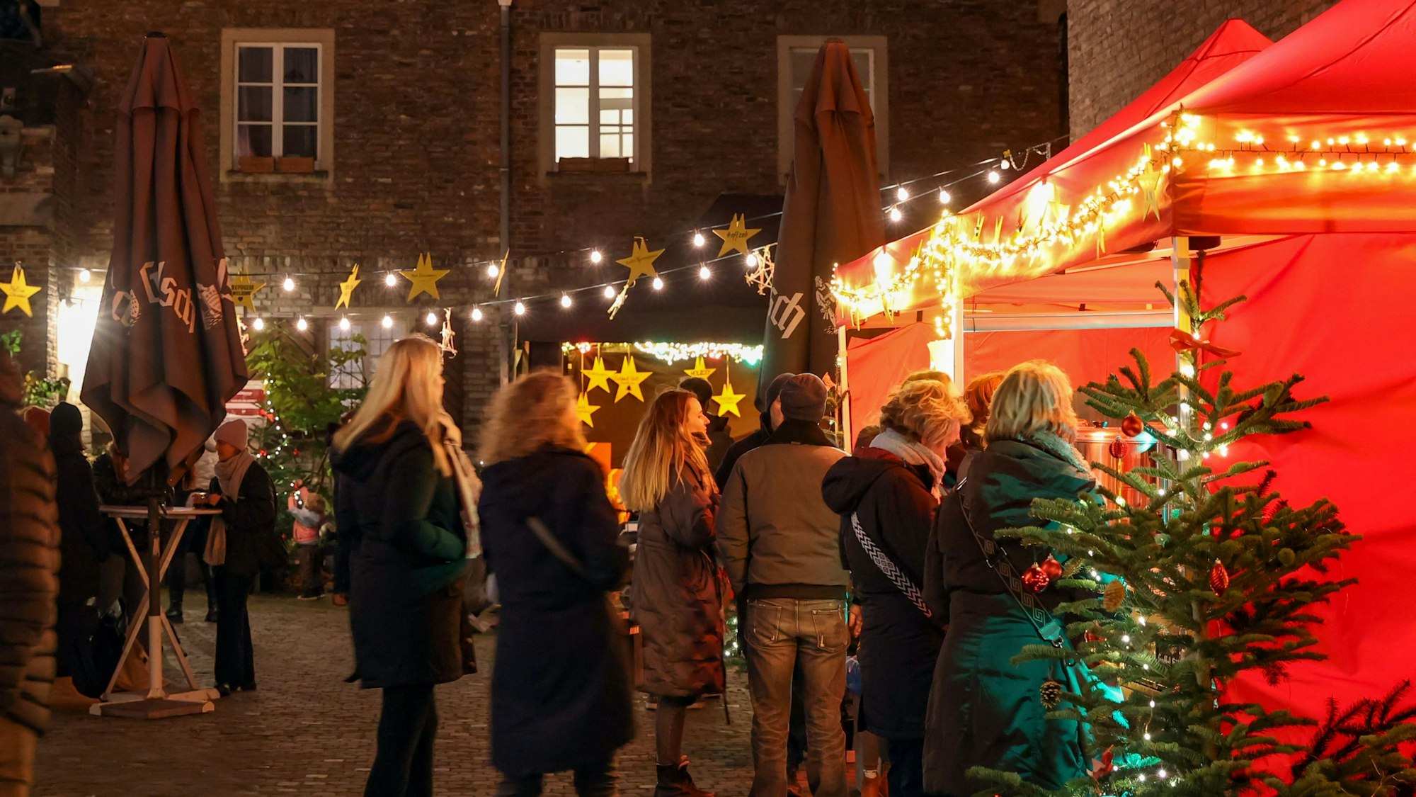 Menschen stehen vor einer Weihnachtsmarkt-Bude.