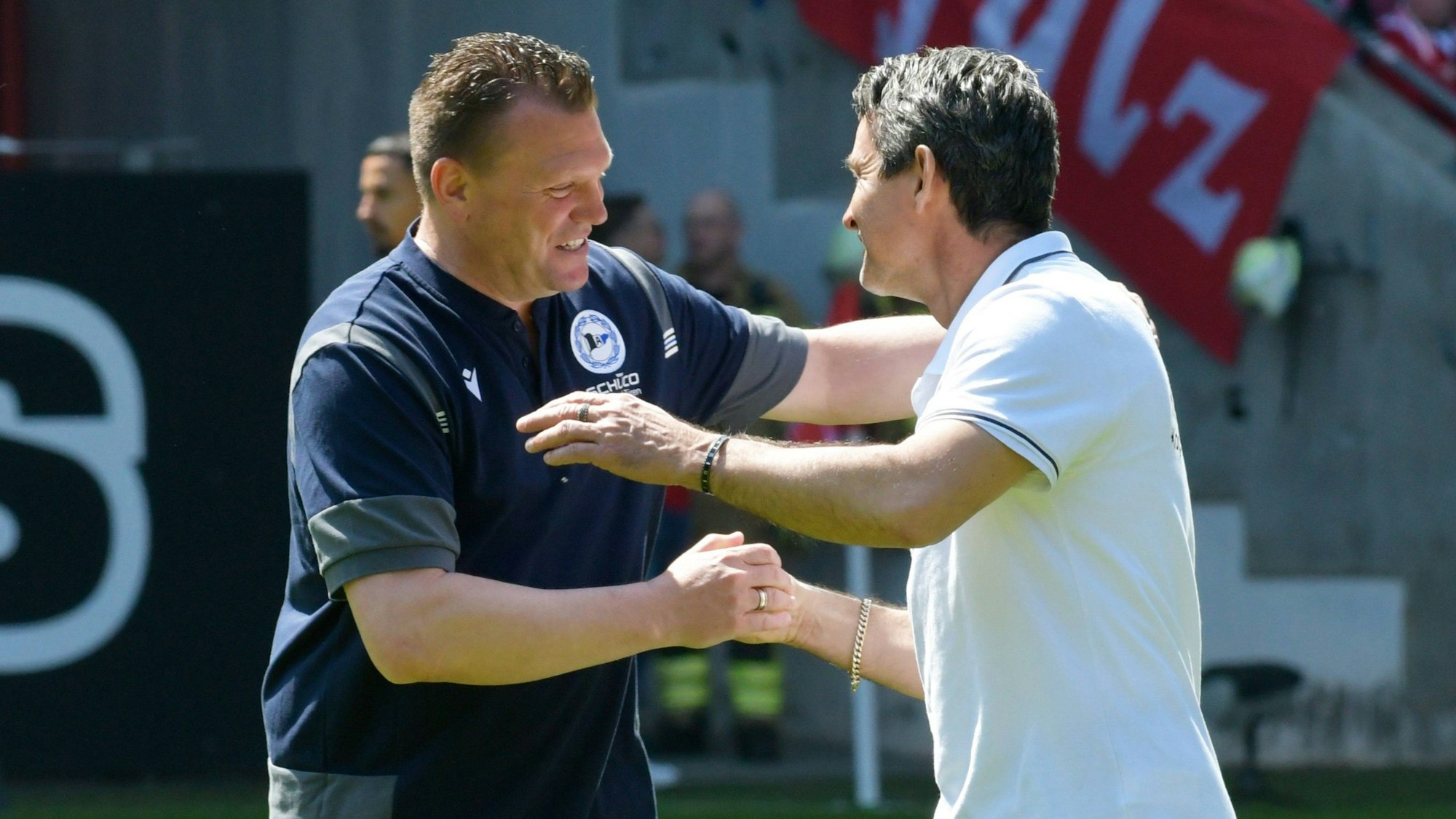 Uwe Koschinat und Dirk Schuster geben sich beim Zweitliga-Spiel zwischen dem 1. FC Kaiserslautern und Arminia Bielefeld lachend die Hand.