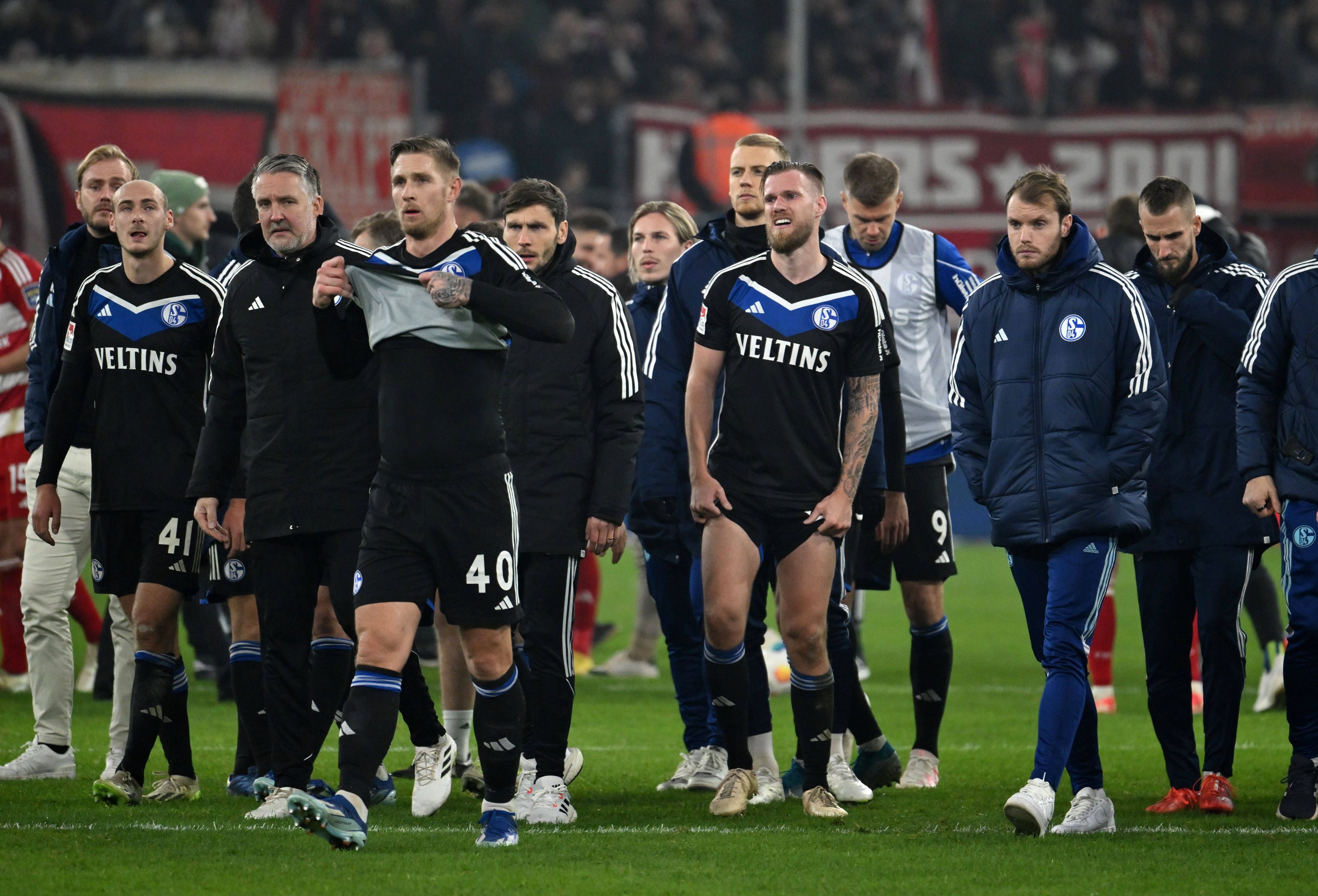 Schalke-Spieler laufen nach der Niederlage gegen Düsseldorf nebeneinander über den Rasen.