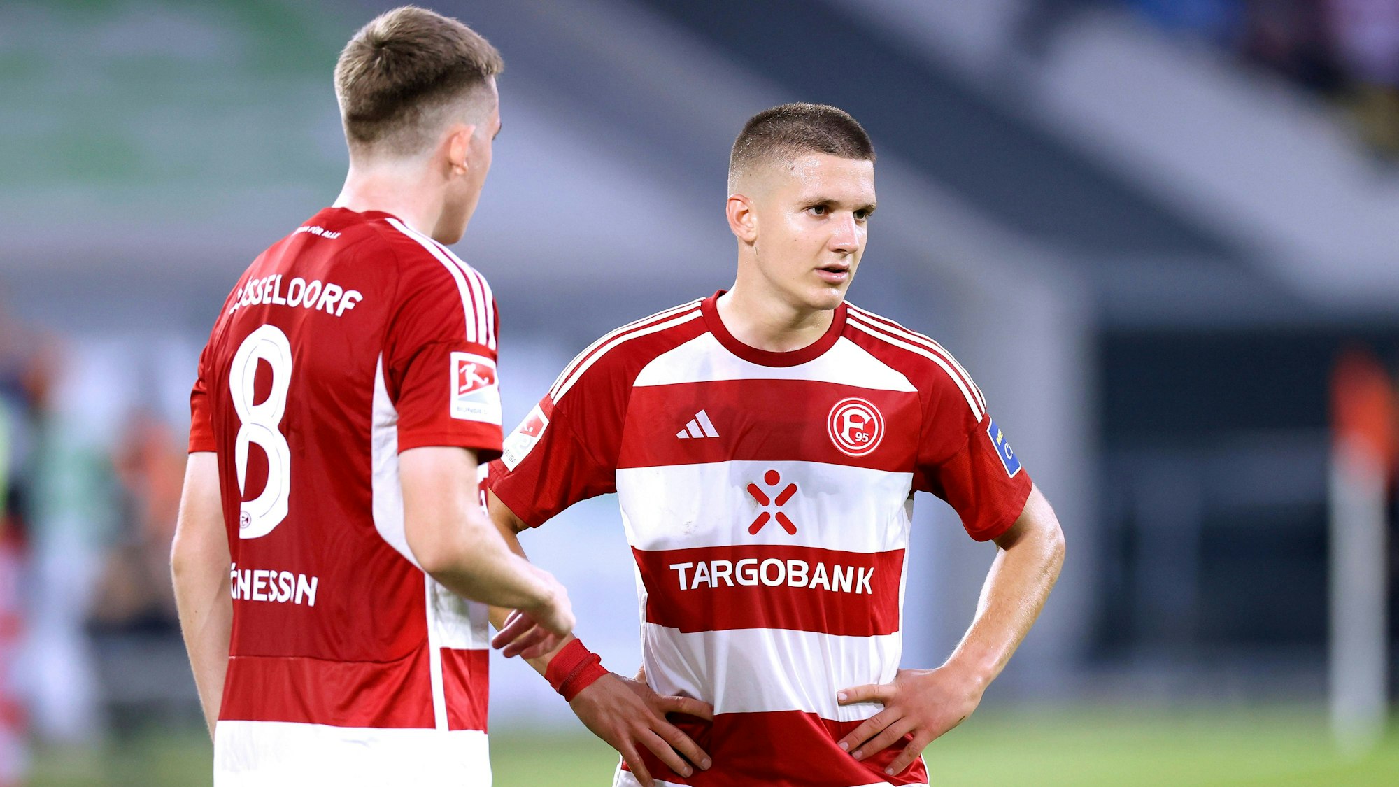 Die Düsseldorfer Profis Isak Johannesson und Christos Tzolis stehen beim Spiel gegen den Karlsruher SC nebeneinander auf dem Platz.