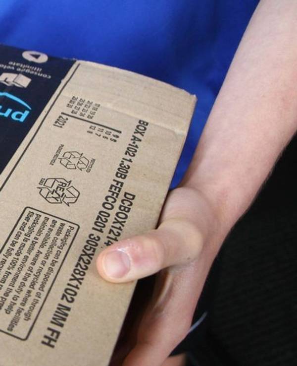 Eine Person hält ein Amazon-Paket in den Händen.