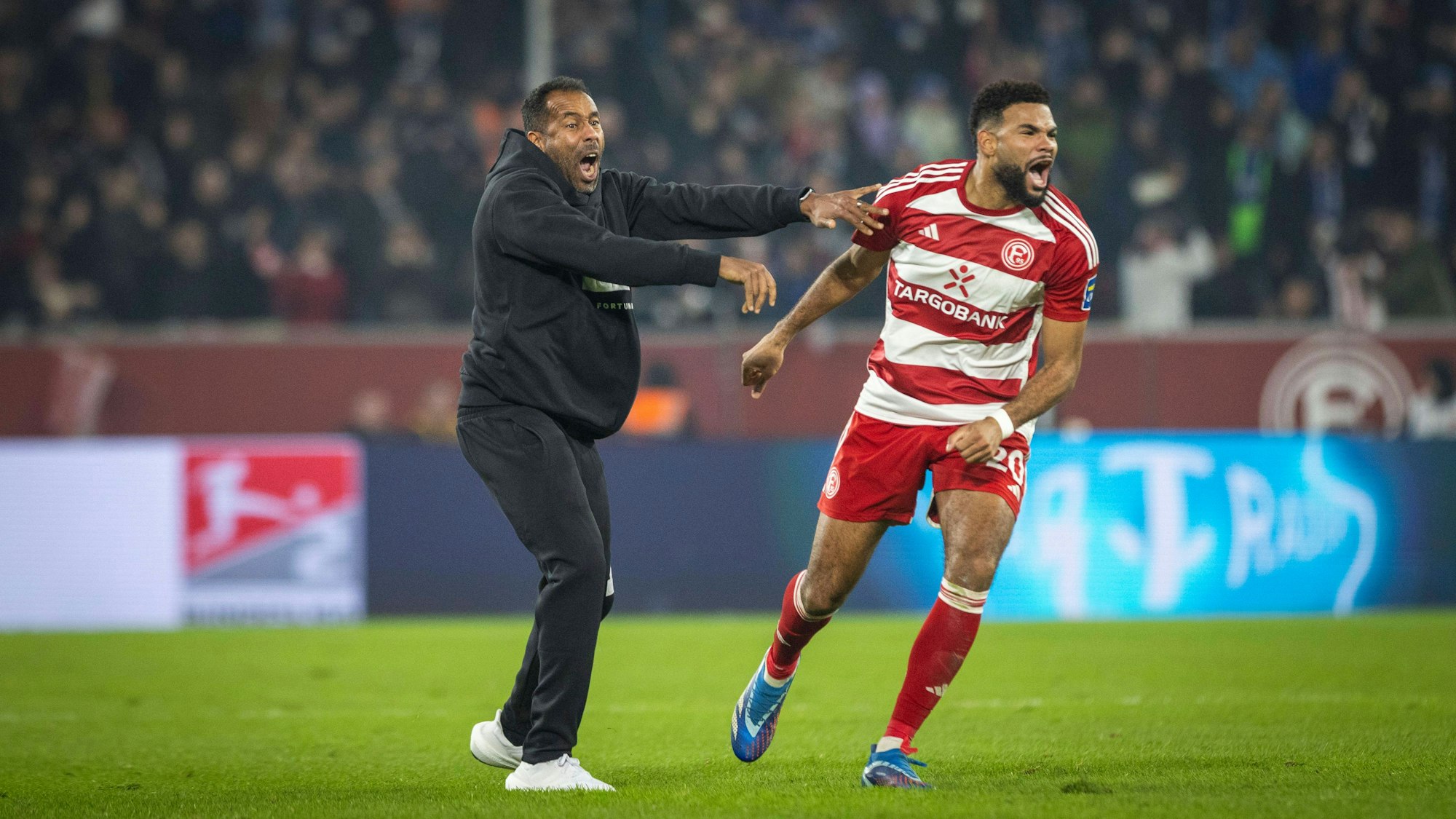 Chefcoach Daniel Thioune (l.) und Jamil Siebert jubeln gemeinsam beim Spiel gegen den FC Schalke 04.