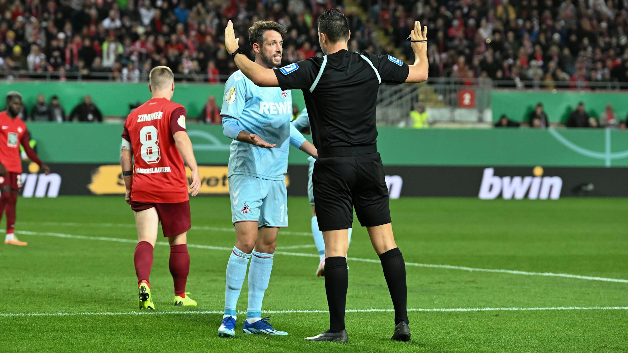 Schiedsrichter Sven Jablonski im DFB-Pokalspiel zwischen dem 1. FC Kaiserslautern und dem 1. FC Köln im Gespräch mit Gäste-Profi Mark Uth.