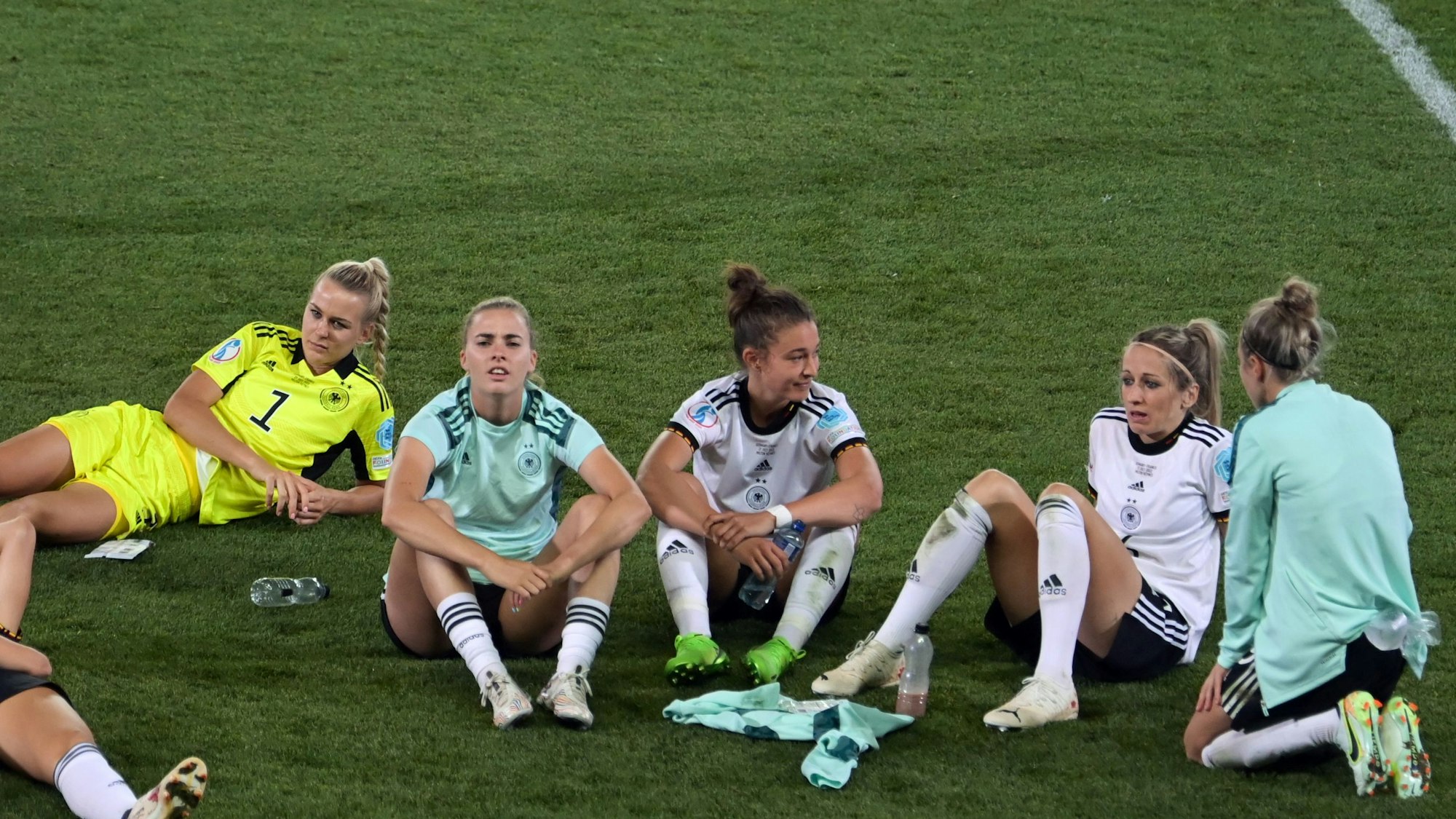 Spielerinnen sitzen nach Spielende auf dem Rasen.