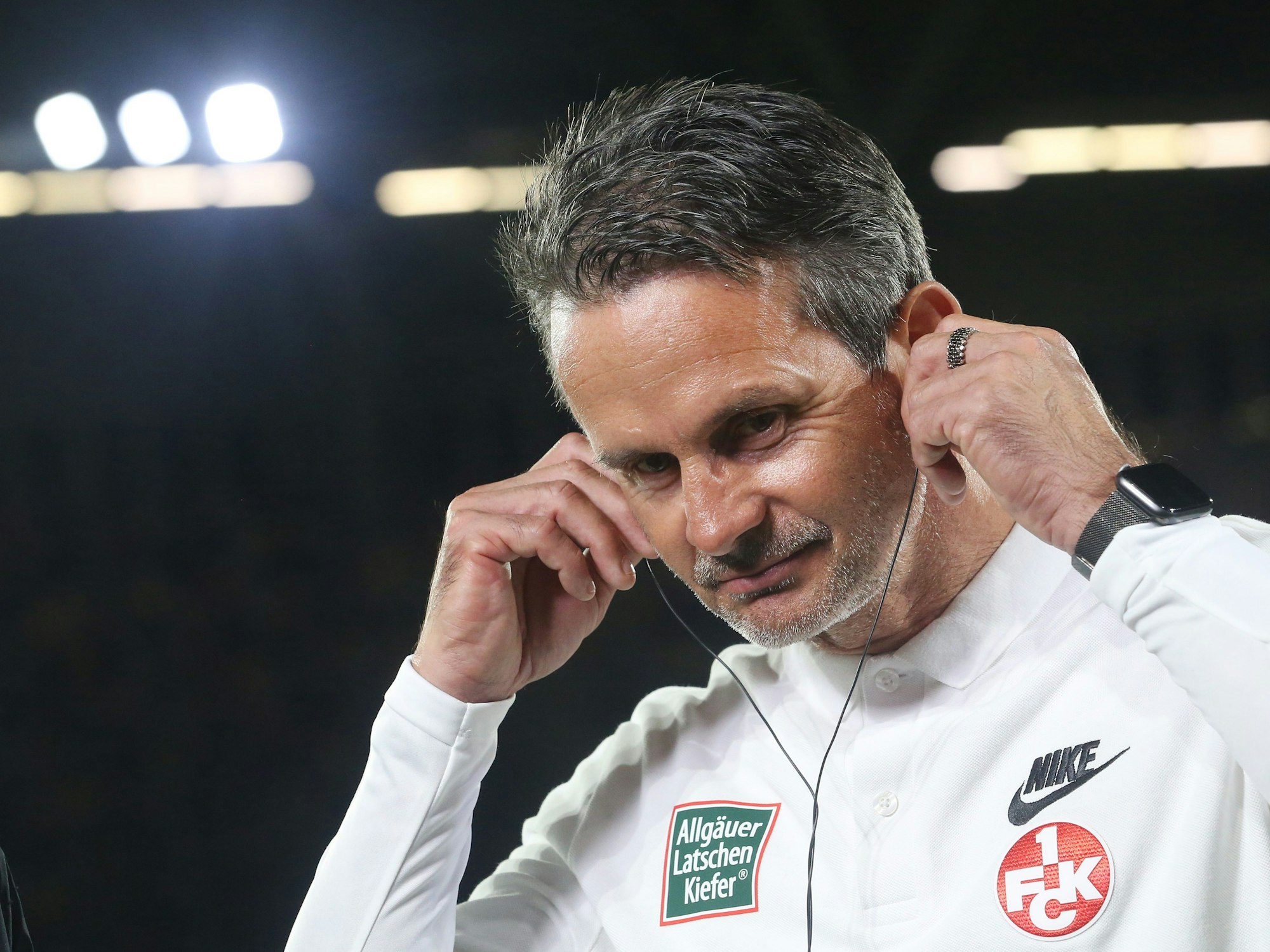 Dirk Schuster zieht sich Kopfhörer an.