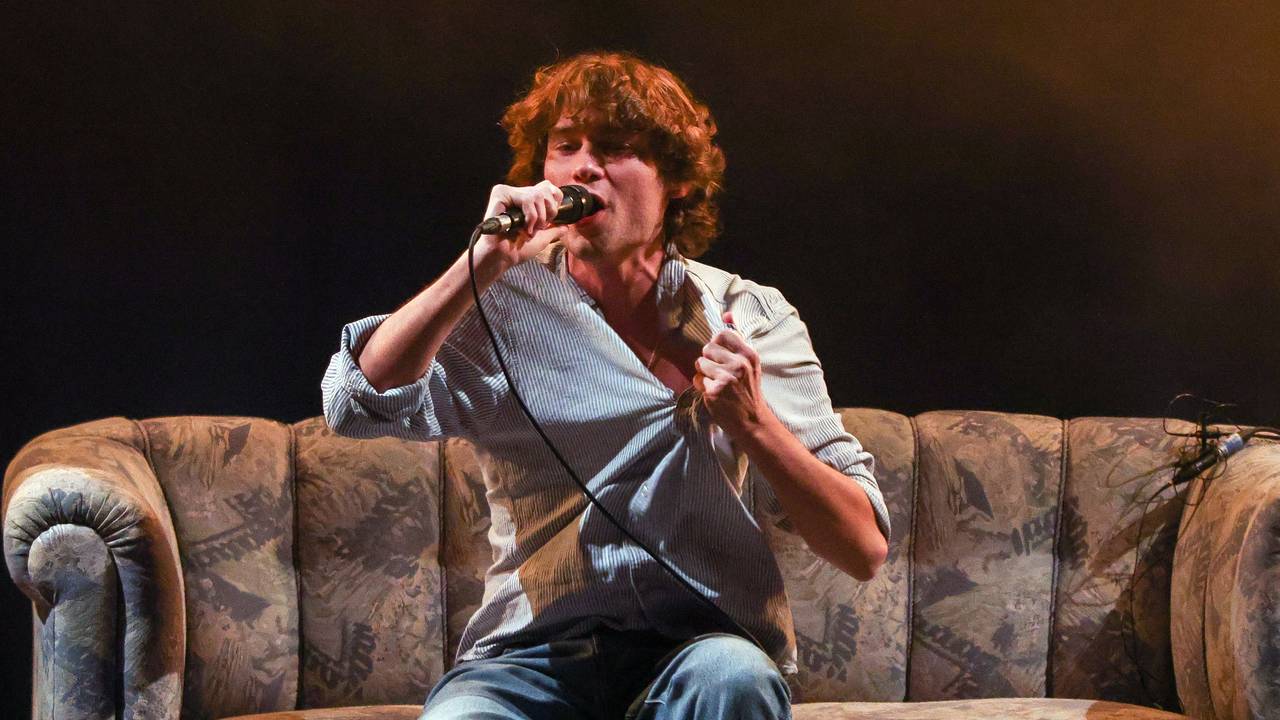 Frontsänger Jeremias Heimbach singt auf einem Sofa bei einem Konzert der Band JEREMIAS.