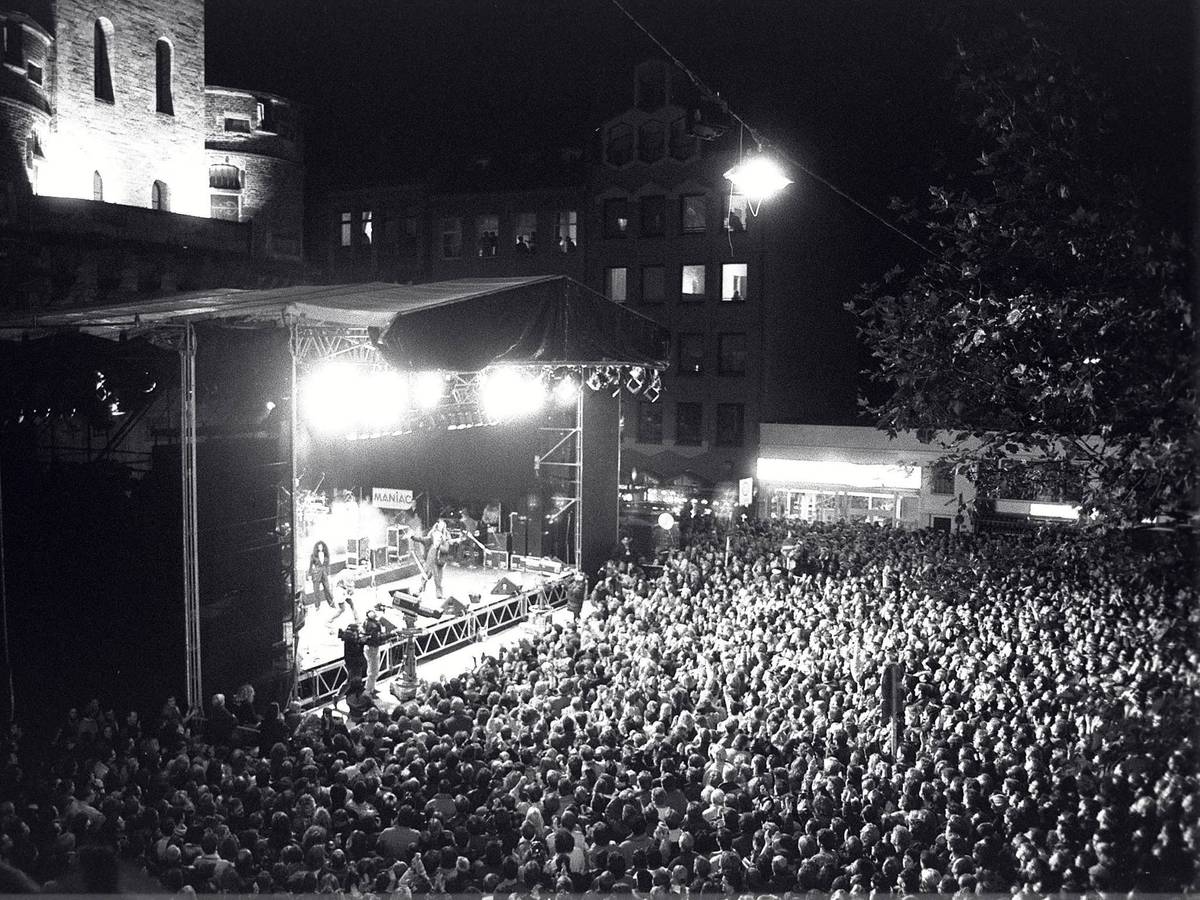Menschen stehen bei einem Konzert vor einer Bühne.