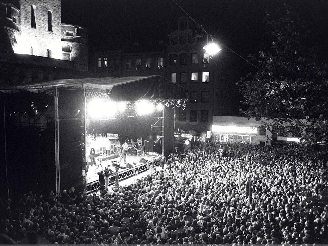 Menschen stehen bei einem Konzert vor einer Bühne.