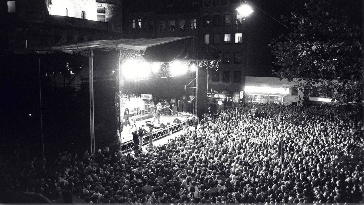 Menschen stehen bei einem Konzert vor einer Bühne.