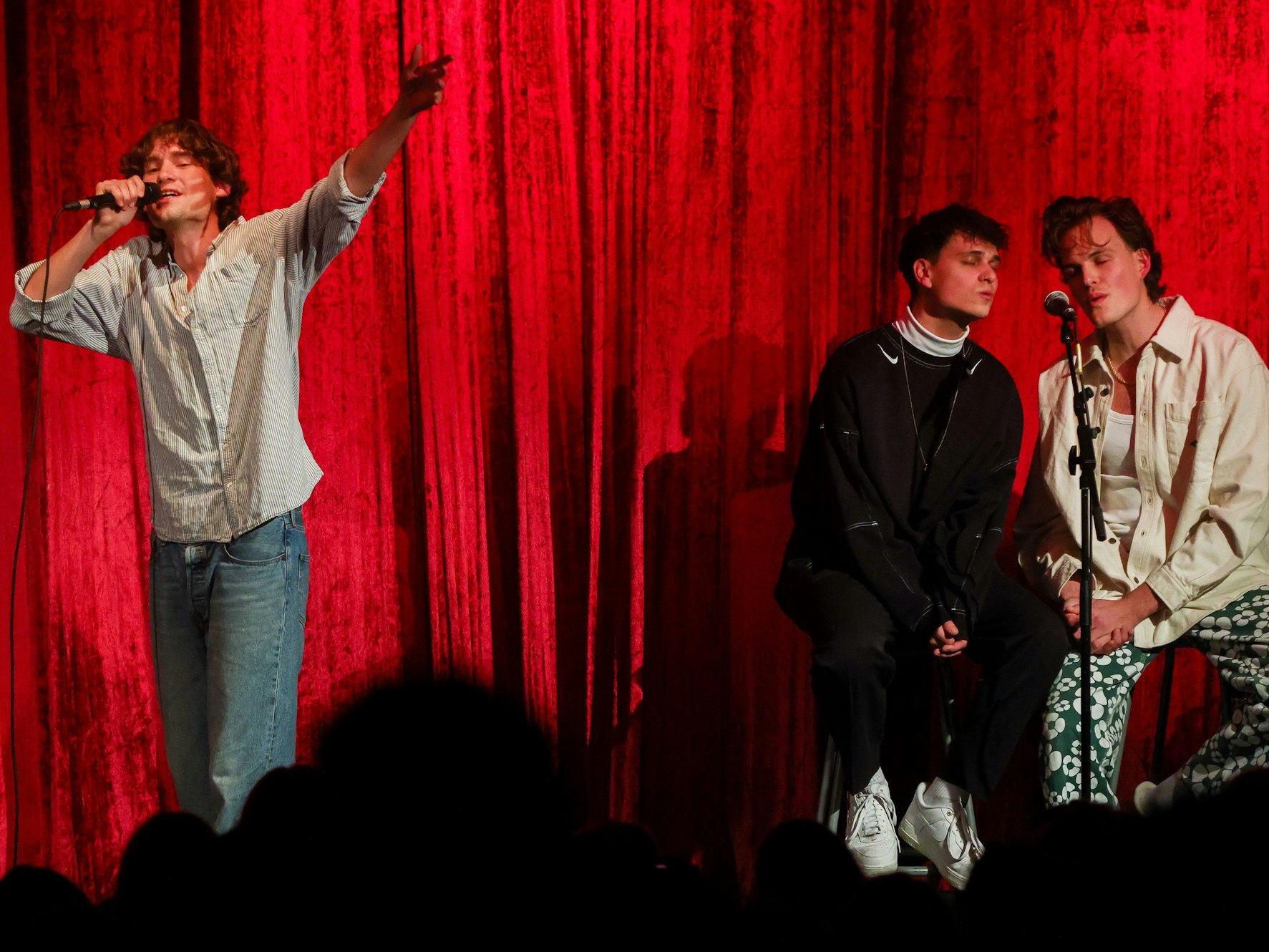 Frontsänger Jeremias Heimbach (l) und Bandkollegen Jonas Herrmann und Ben Hoffmann singen vor einem roten Vorhang im Gloria Theater Köln.