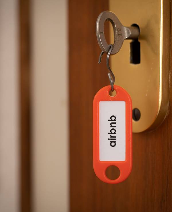 „airbnb“ steht auf einem Schlüsselanhänger, der in einer Tür steckt.