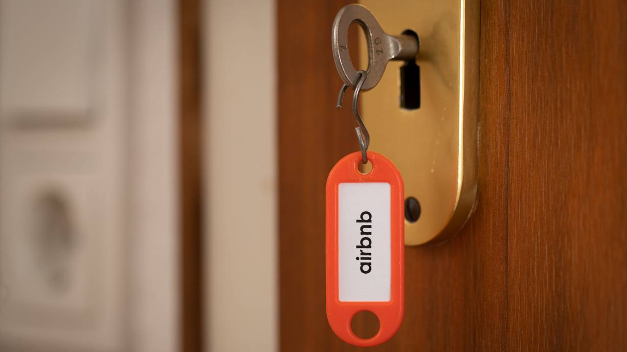 „airbnb“ steht auf einem Schlüsselanhänger, der in einer Tür steckt.