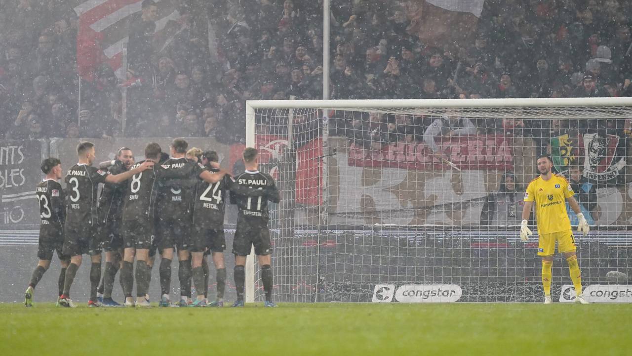 Die Spieler vom FC St. Pauli jubeln nach dem Tor zum 2:0 während Torhüter Daniel Heuer Fernandes vom HSV die Szenerie verfolgt.