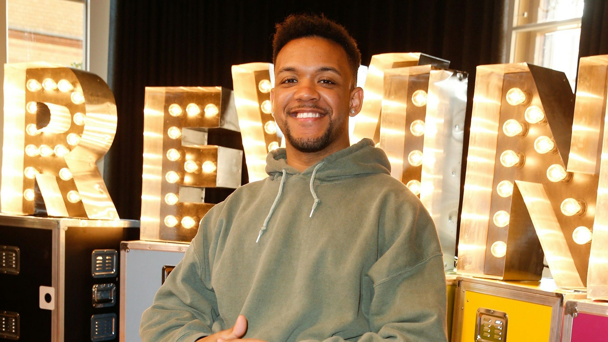 Leeroy Matata, sitztend im Rollstuhl, grinst in die Kamera.