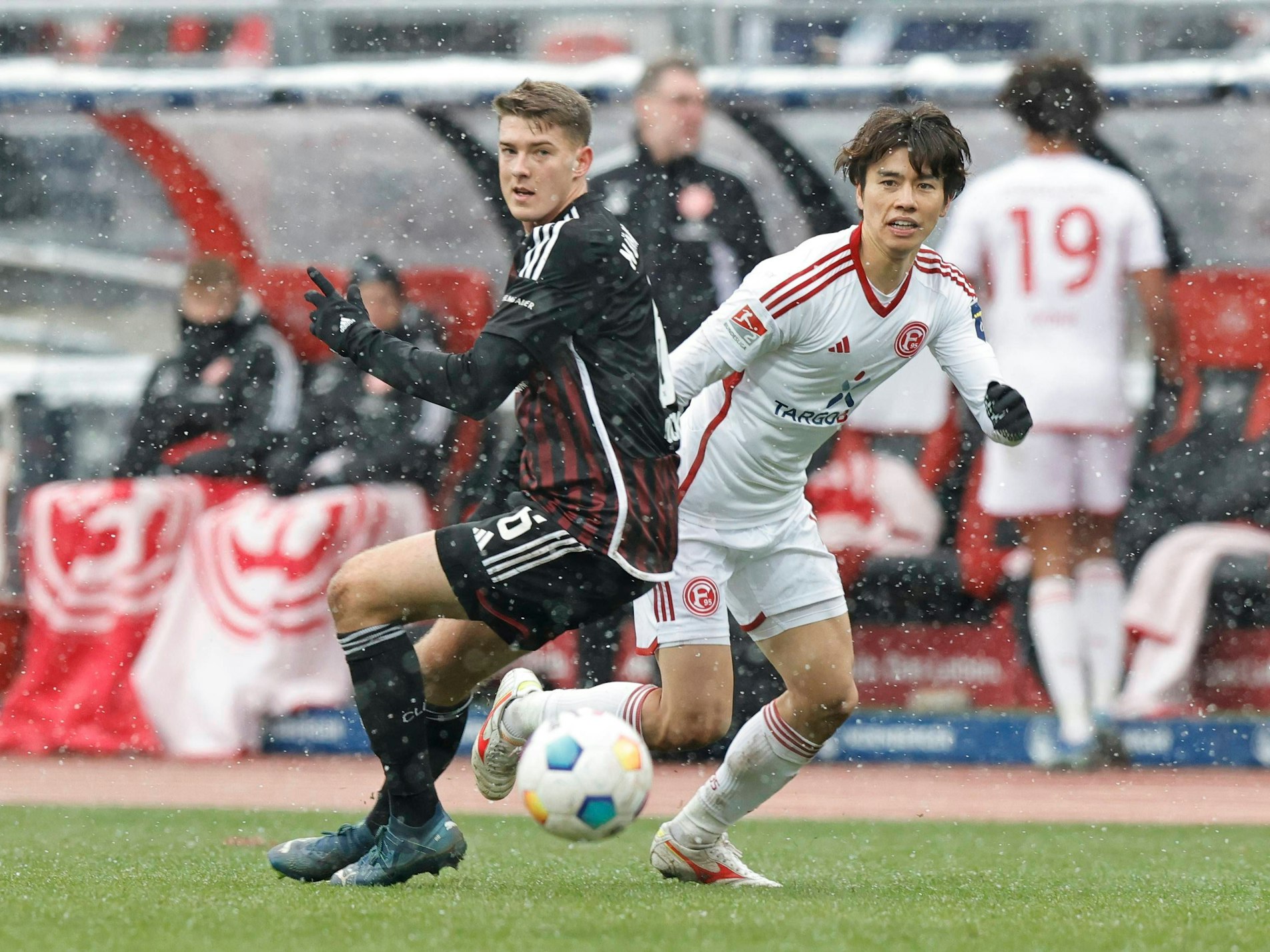 Nürnbergs Florian Flick und Fortuna Düsseldorfs Ao Tanaka blicken gemeinsam in Richtung des Balls.