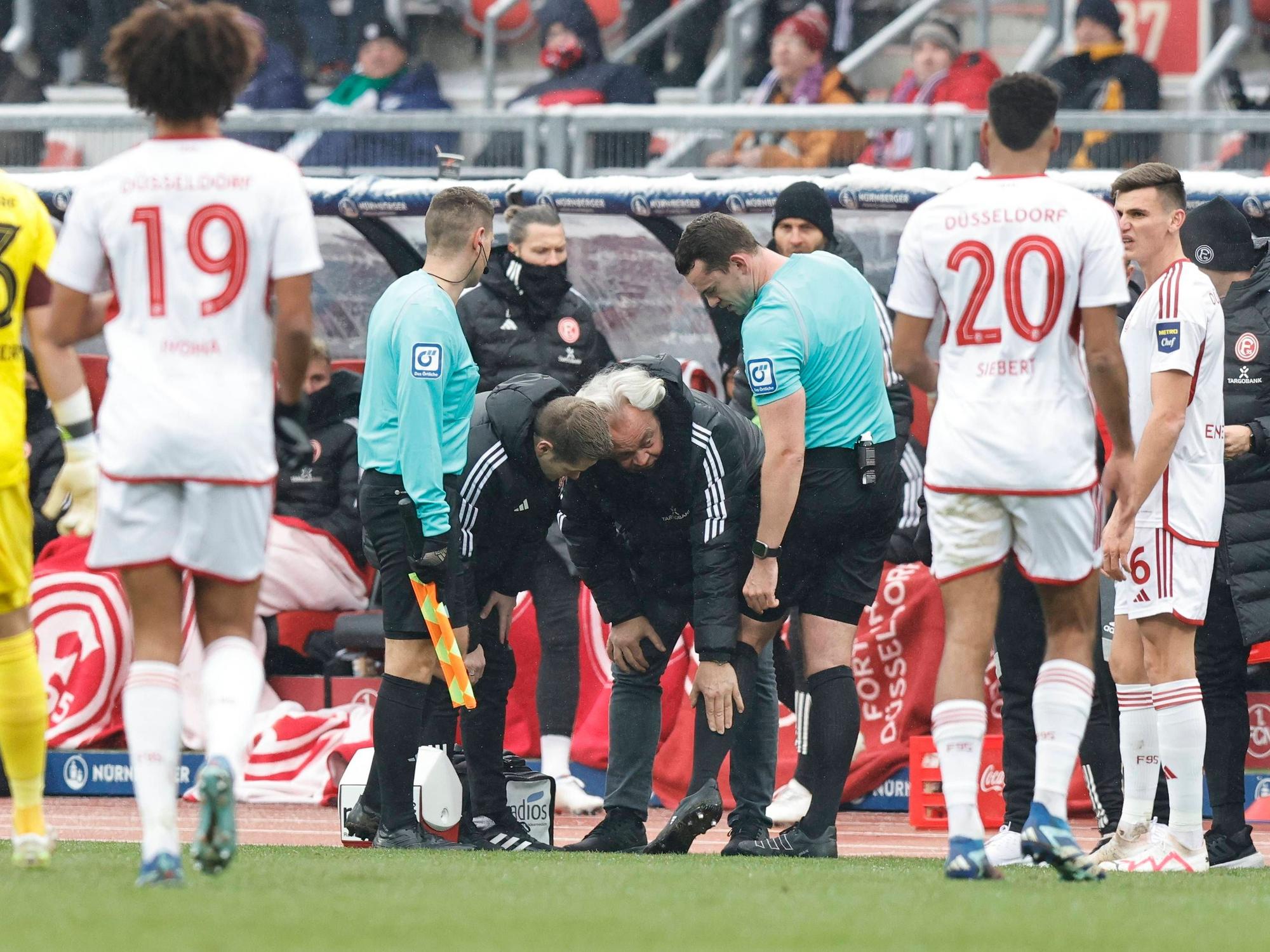 Schiedsrichter Richard Hempel wird am Seitenrand vom Düsseldorfer Teamarzt Ulf Blecker an der Wade behandelt.
