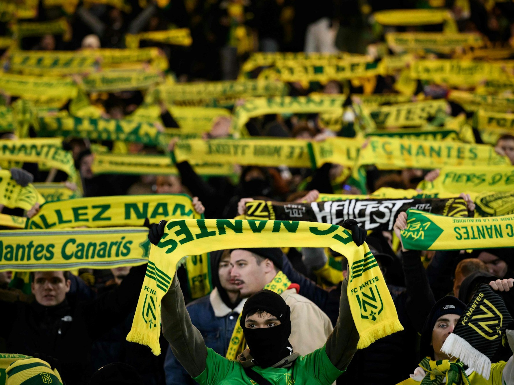 Die Fans des FC Nantes halten ihr Schals auf der Tribüne hoch.