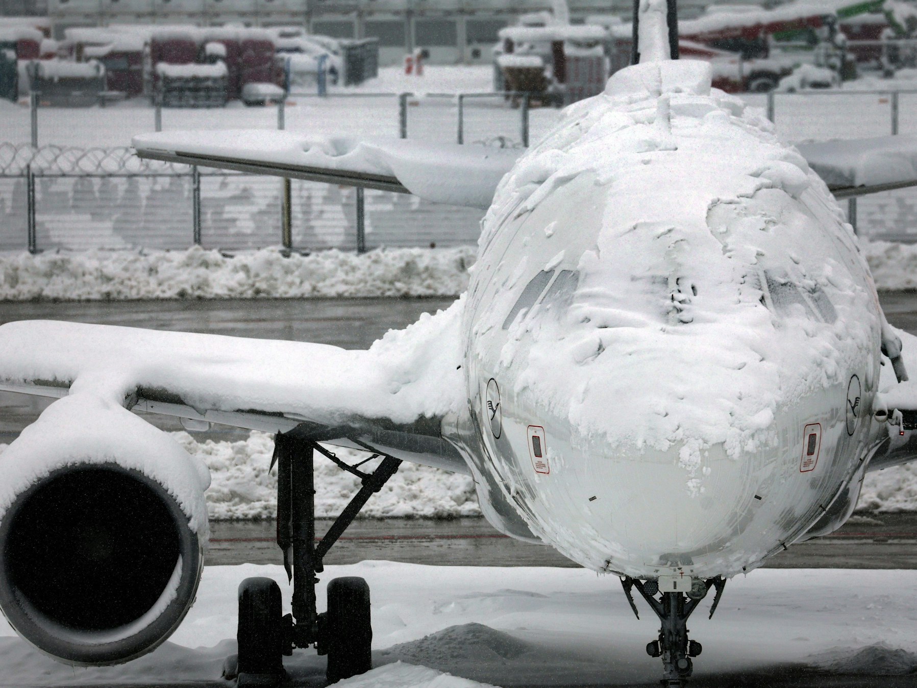 Ein verschneites Flugzeug steht am Flughafen.
