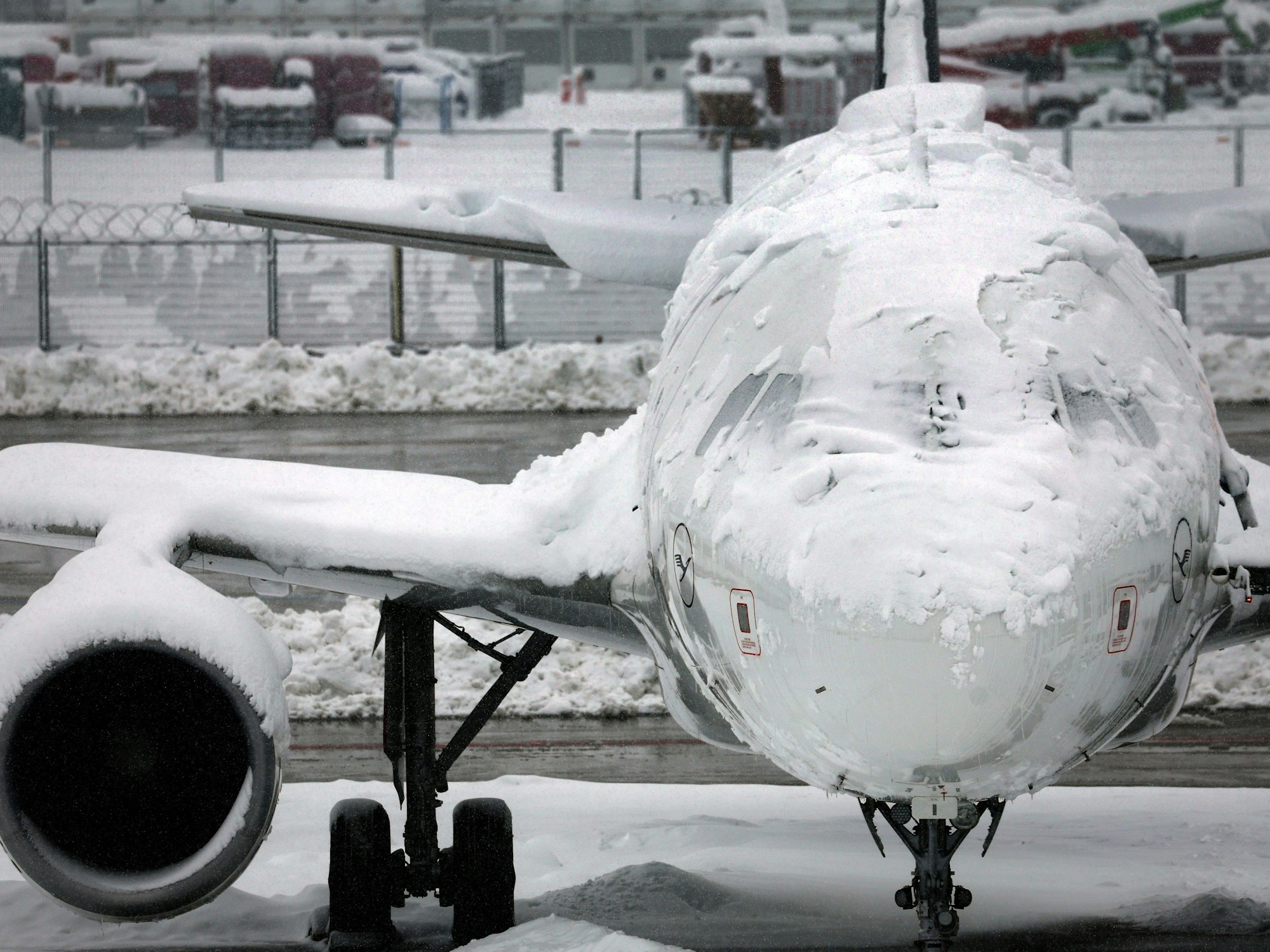 Ein verschneites Flugzeug steht am Flughafen.