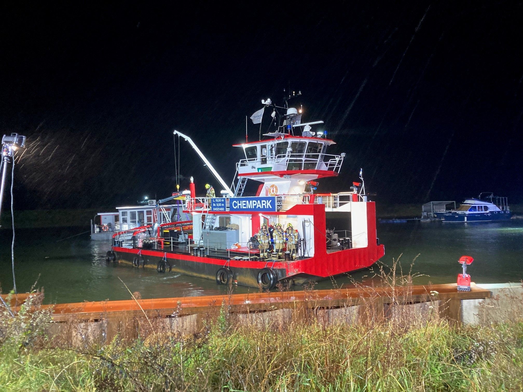Ein rotes Schiff steht in der Dunkelheit an einem Anleger.