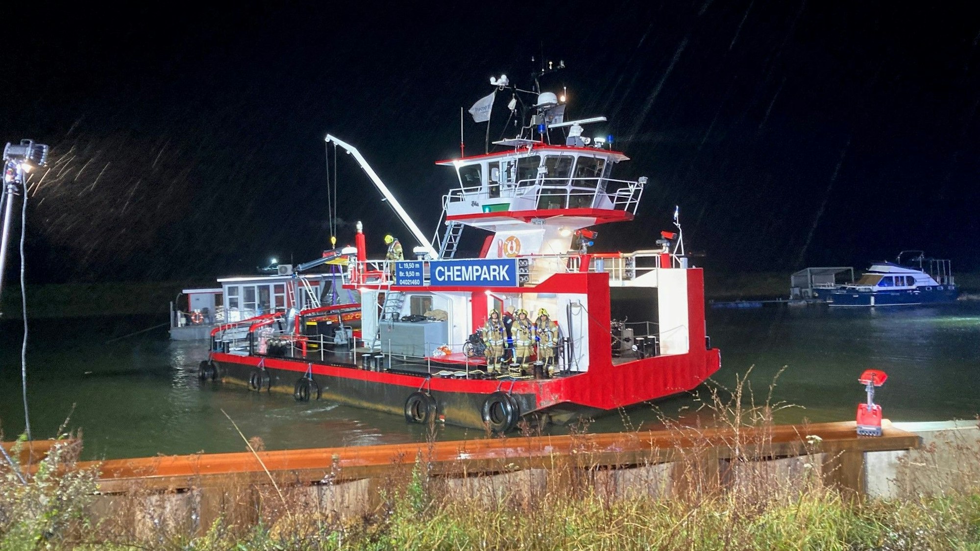 Ein rotes Schiff steht in der Dunkelheit an einem Anleger.