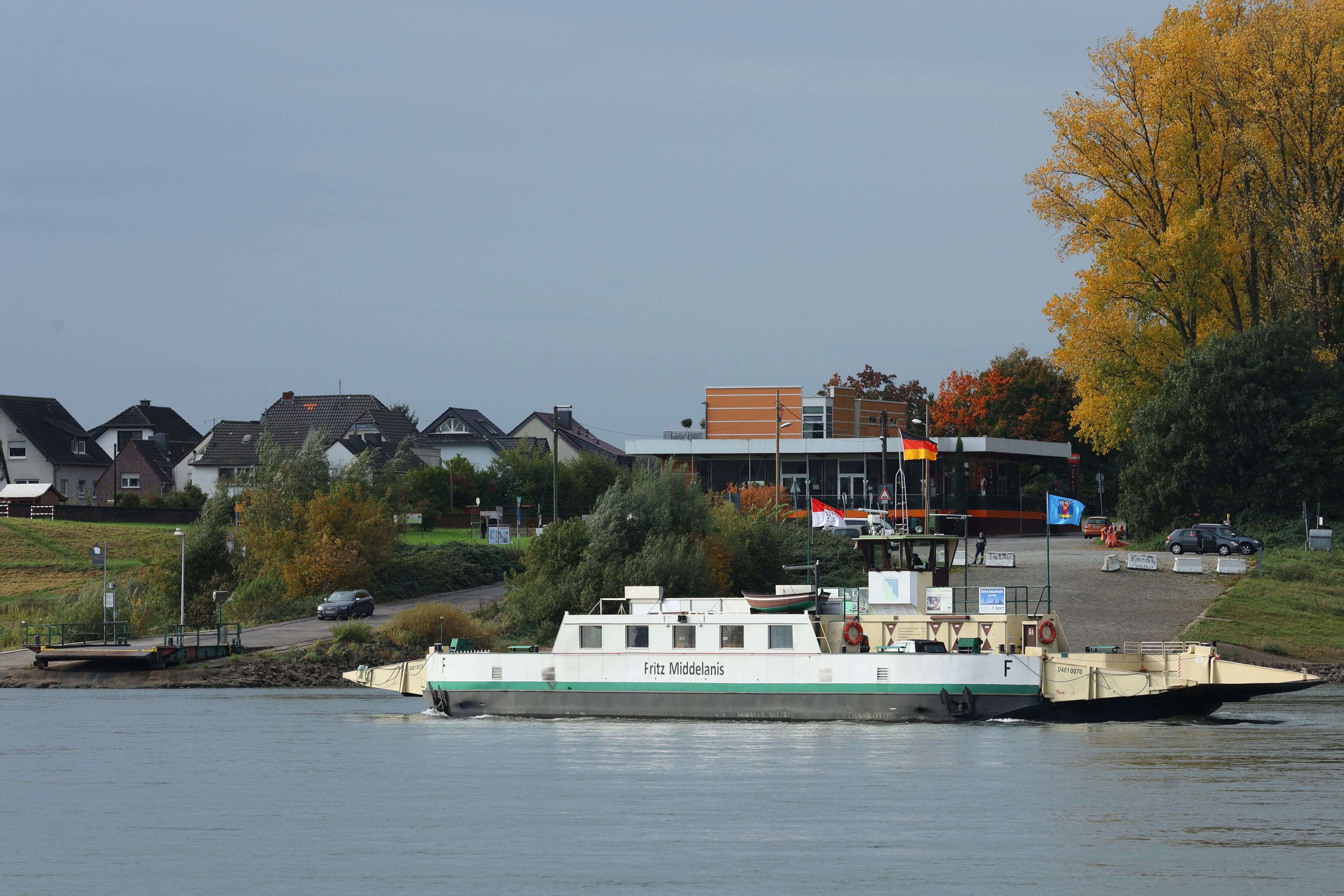 Die Rheinfähre Fritz Middelanis auf dem Rhein. Ein weißes Schiff mit grünen Applikationen.