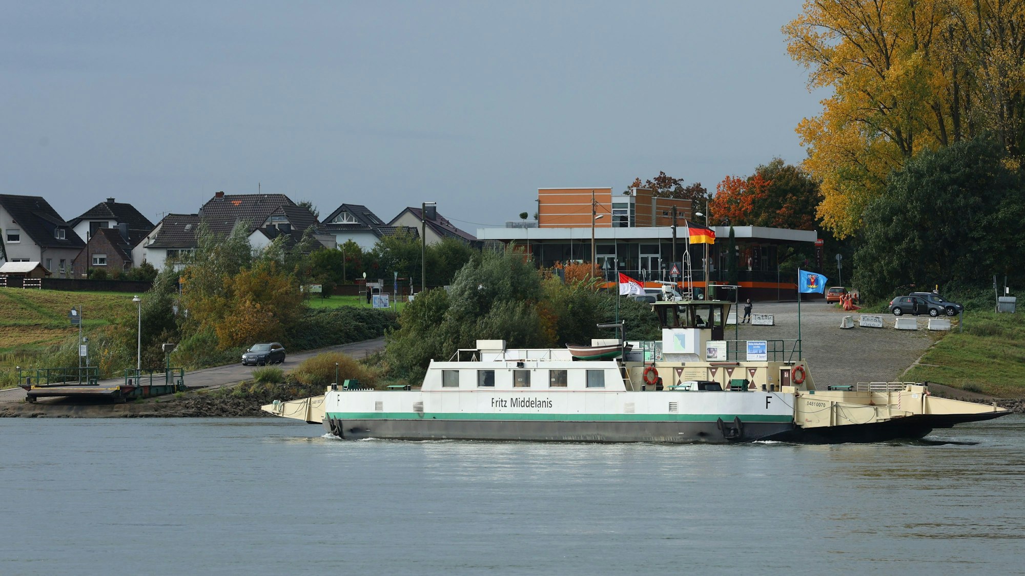 Die Rheinfähre Fritz Middelanis auf dem Rhein. Ein weißes Schiff mit grünen Applikationen.